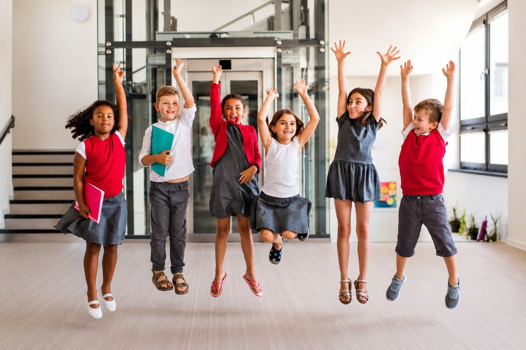 Children jumping together in a school hallway
